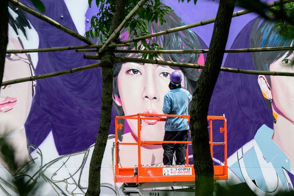 An artist spray paints a mural of K-pop megastars BTS in Seoul on June 12, 2023, on the occasion of the supergroup's 10-year anniversary.
Image: Anthony Wallace / AFP 