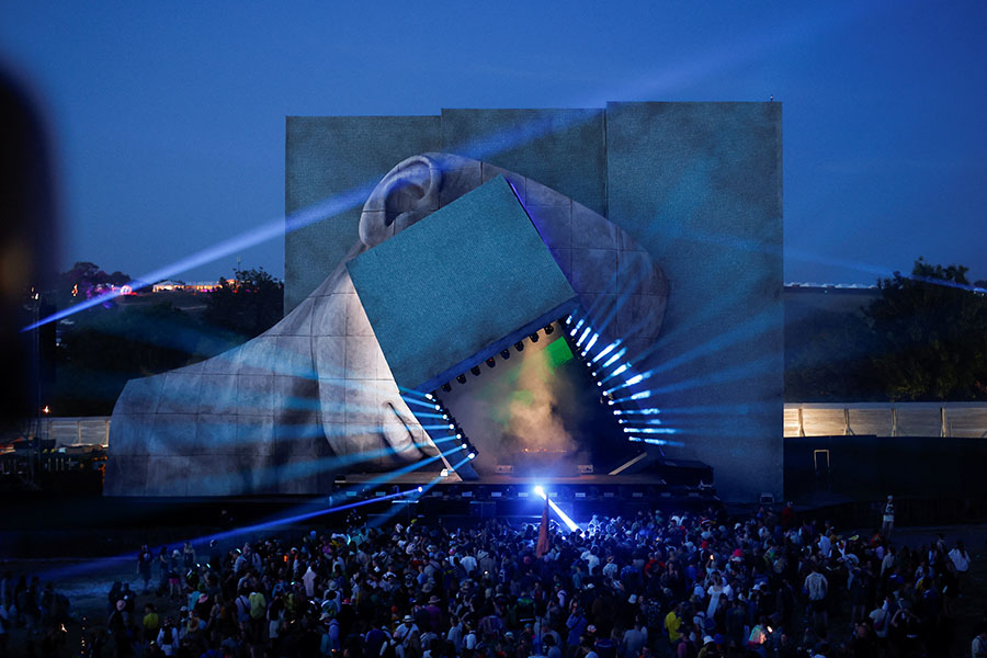 Revellers throng to IICON, the immersive audio-visual arena. The sculptural head artwork, animated by state-of-the-art video mapping, delivers a vision of future music from the cutting edge of today’s underground. Glastonbury Festival site, Somerset, Britain, June 22, 2023. 
