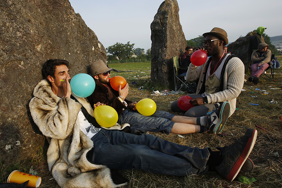 Festival goers inhale ‘laughing gas’ at sunrise at the stone circle at Glastonbury music fest 2013.